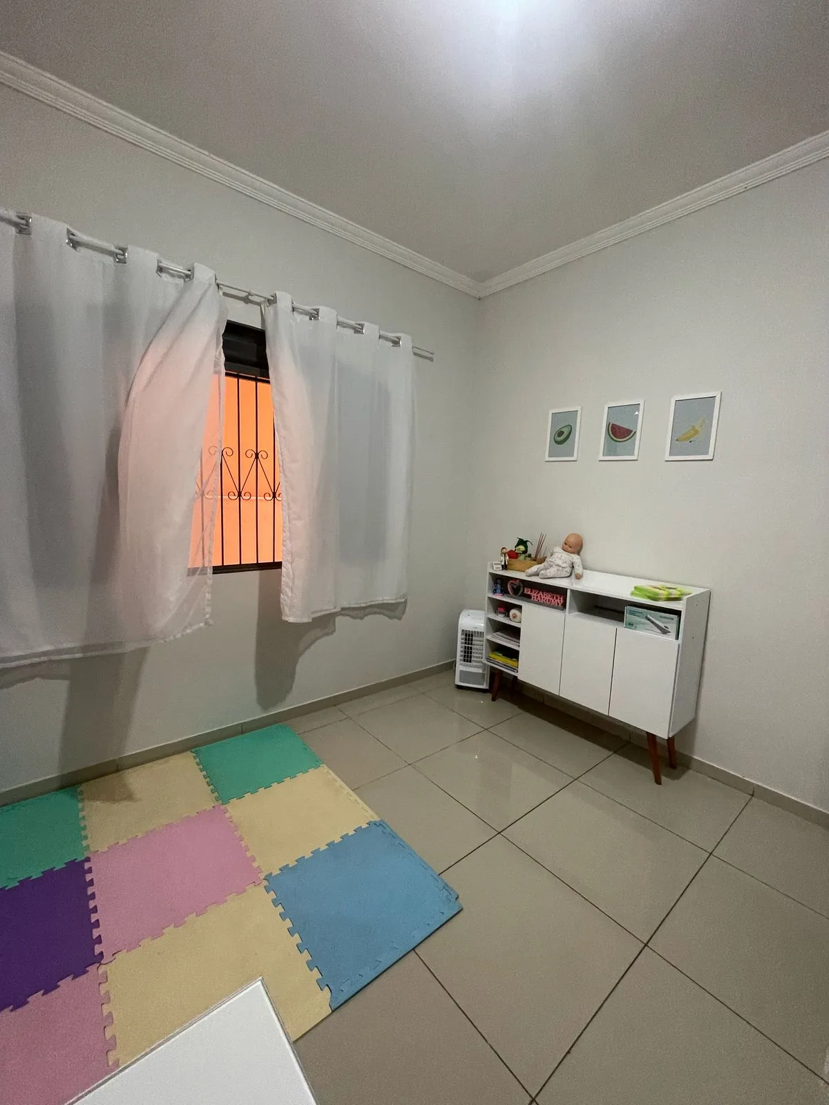 Sala de atendimento com tapete colorido de encaixe, móvel com brinquedos e quadrinhos na parede